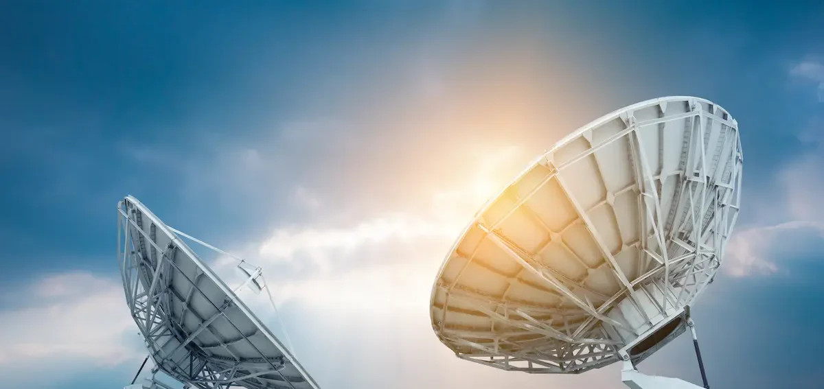 Bild mit 2 großen Radioteleskopen die zum blauen Himmel ausgerichtet sind